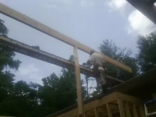 Carpenter setting a ridge beam over a new addition frame — Ice Dam Removal by Roofing Brothers in Rose