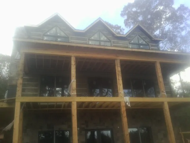 Dormers and porch framing on a large log home under construction — Roof Coating work by our crew in Rose