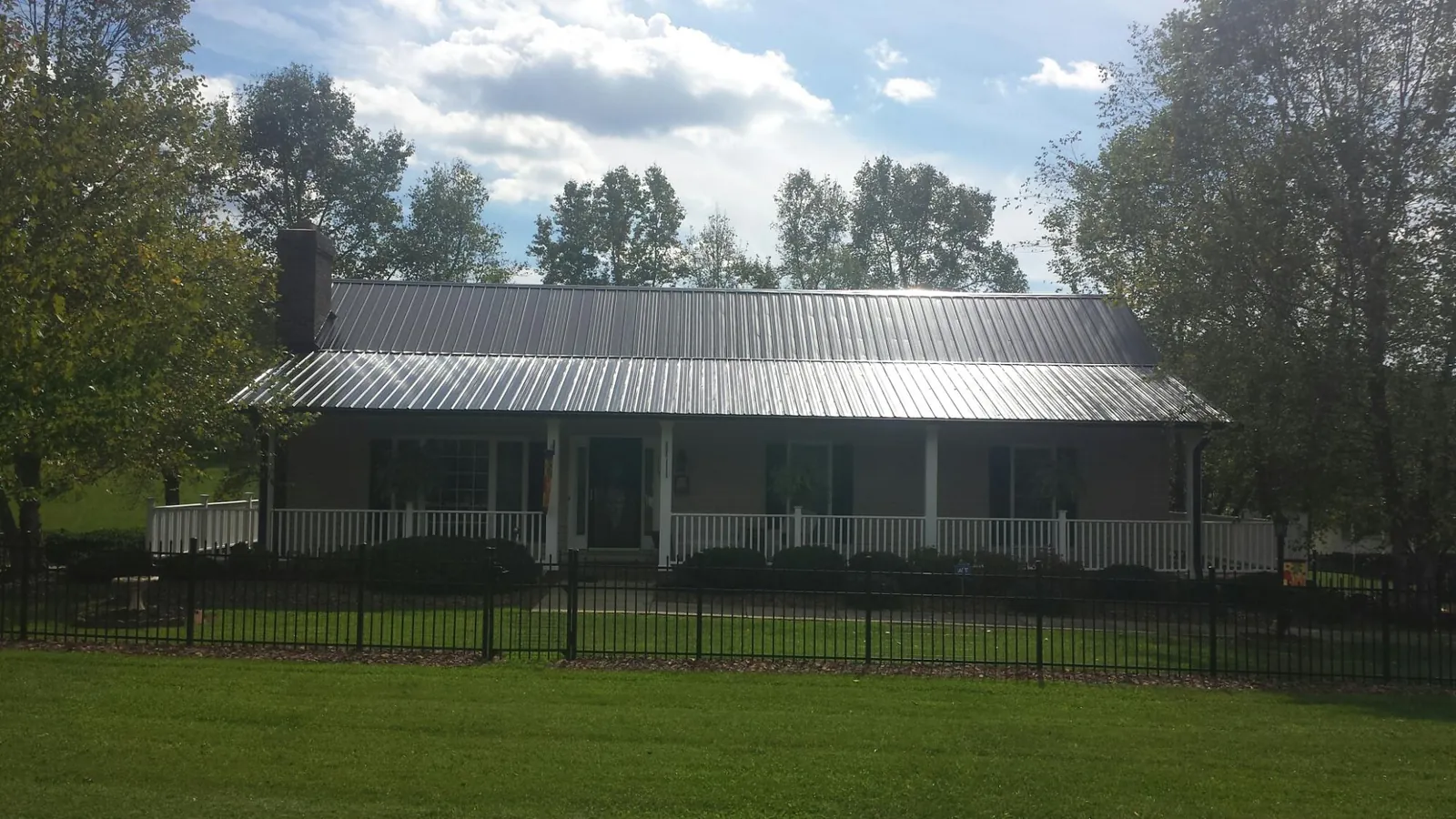 Gray metal roof on a brick ranch with a full width front porch — Gutter Guard Installation work by our crew in Rose